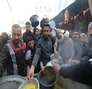 عائلات نازحة تتجمع للحصول على وجبات مجانية من مطبخ خيري في مخيم النصيرات للاجئين، وسط تعليق عمل العديد من المنظمات الإنسانية بسبب القيود الإسرائيلية وتقليص دخول المساعدات